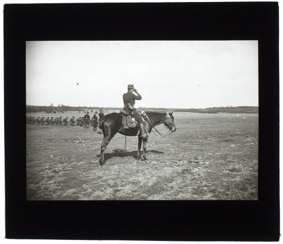 [Un exercice de tir durant une campagne de manoeuvres militaires dans la Somme. Un officier à cheval observe avec des jumelles les tirs]