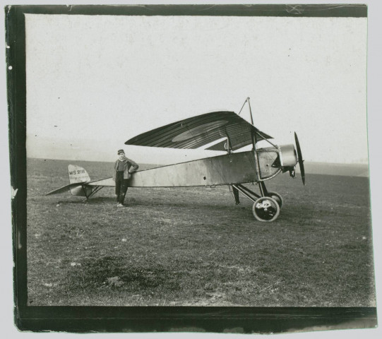 Photographie montrant un avion de chasse monoplan Morane-Saulnier Type L, de Garros, au sol, avec un pilote posant devant l'appareil