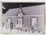 [Fête de Jeanne d'Arc à Camiers - octobre 1909. Devant la foule, deux hommes montés sur une échelle placent une statuette de la Vierge dans une niche sur la façade d'un édifice du village]