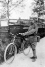 Portrait d'Arthur Lorge en uniforme avec sa bicyclette près d'une péniche