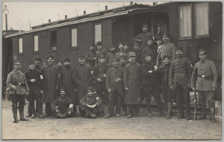 CARTE PHOTO MONTRANT DES PRISONNIERS FRANCAIS (TENUE 1914) DEVANT UN WAGON, ENCADRES PAR DES SOLDATS ALLEMANDS