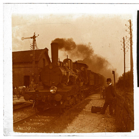 Gare de Blangy-Tronville. Arrivée d'un train à vapeur. Un homme au chapeau melon attend sur le quai de la gare