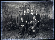 Sept jeunes garçons dans un jardin, dont un tenant un fusil