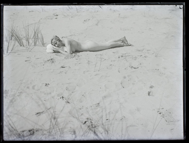 [Une jeune femme nue allongée dans le sable]