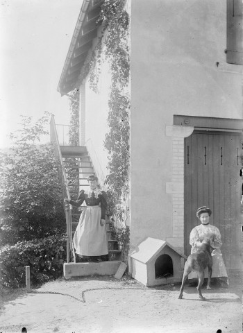 Portrait de famille de M Durand, deux femmes avec un chien devant une maison