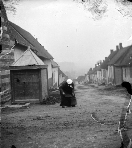 Scène rurale. Une vieille femme portant un lourd panier