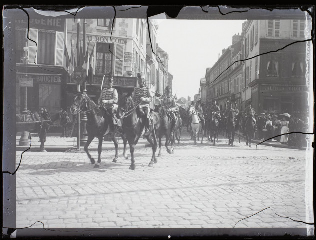 [Passage de militaires à cheval dans les rues d'Amiens, près de la place Saint-Denis (actuelle place René Gobelet). De nombreux commerces : boucherie, "Au Bon Coin", etc]