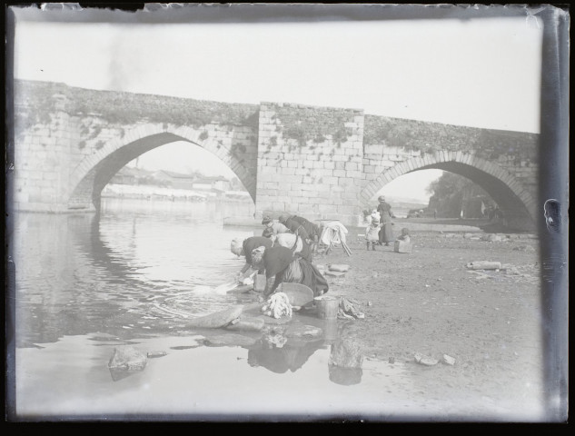 [La lessive : femmes occupées à laver le linge dans une rivière près d'un pont]