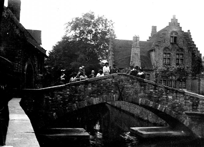 Scène de voyage. Un groupe posant sur un pont de pierres et une maison flamande à redents