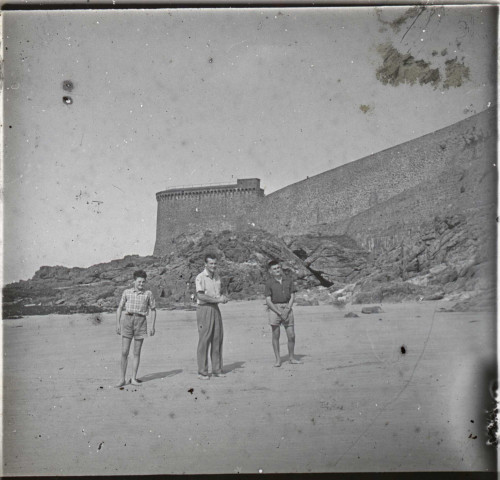 [Trois jeunes gens sur la plage de Saint-Malo devant les remparts et la tour Bidouane. Ce cliché semble postérieur à la mort de F. Poidevin]