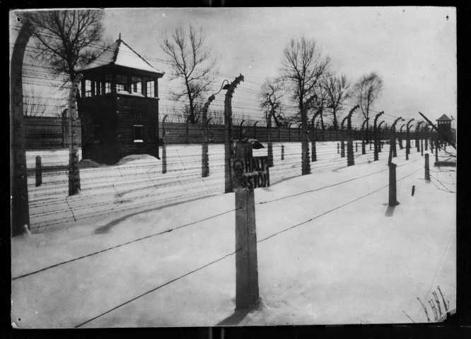 Vue extérieure d'un camp de concentration. Les clôtures de fils électrifiés, les fils de fer barbelés et un mirador