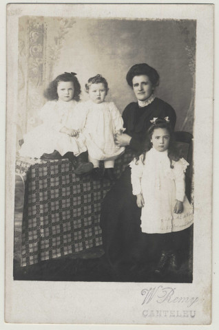 Photo studio représentant trois enfants et une femme, Marie Lemaire, assise sur une chaise