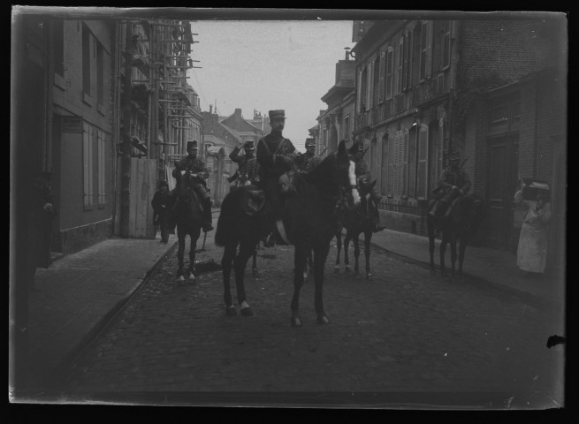 [Chasseurs à cheval dans une rue d'Amiens. Au second plan à gauche, on distingue un échafaudage sur la façade d'une maison]